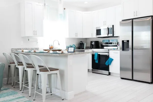 a kitchen with stainless steel appliances kitchen island granite countertop a table chairs microwave and sink