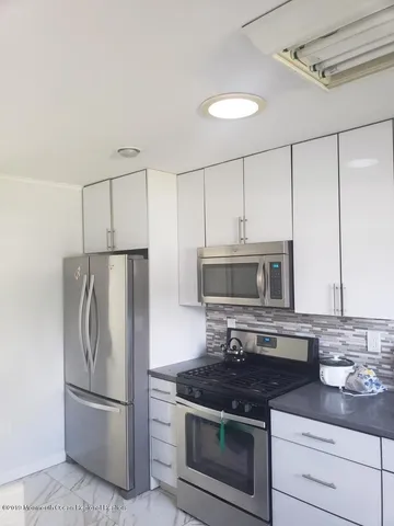 a kitchen with stainless steel appliances granite countertop a stove a refrigerator and a microwave