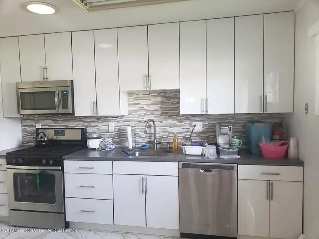 a kitchen with white cabinets and sink