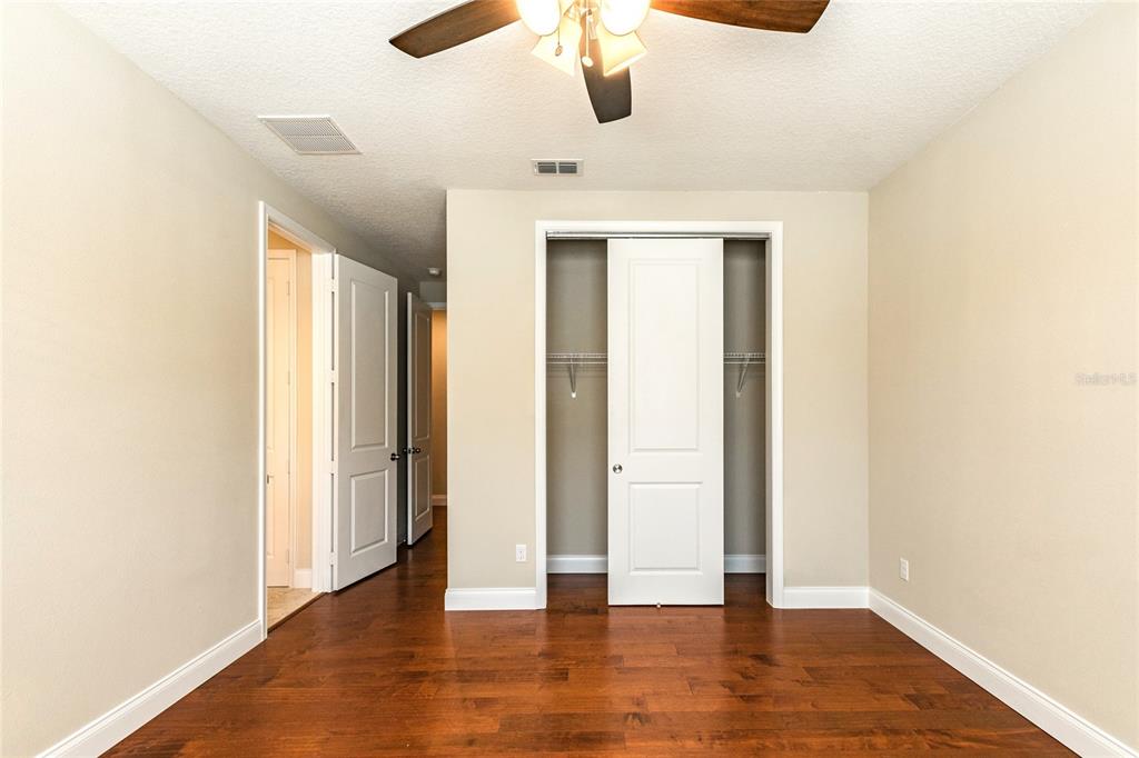 8278 Procida Isle Lane Windermere, FL 34786 - Photo 66 of 90 an empty room with wooden floor chandelier fan and windows
