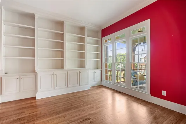 a view of an empty room with a window and wooden floor