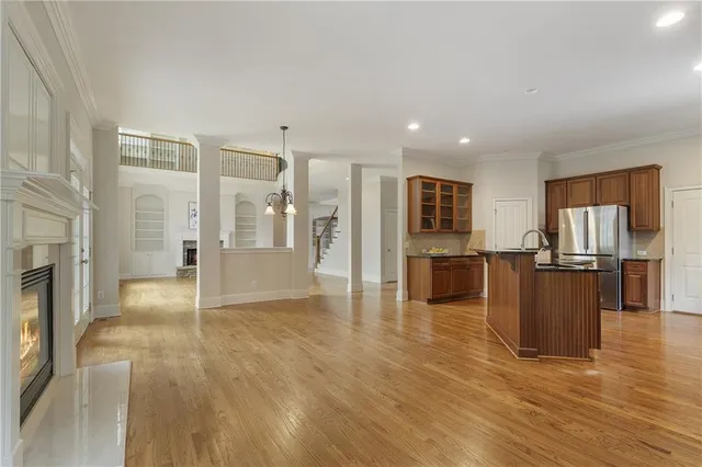 a view of a living room kitchen with stainless steel appliances wooden floor and large windows