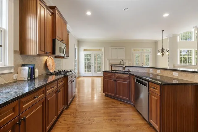 a kitchen with stainless steel appliances granite countertop wooden cabinets a sink dishwasher a stove and a refrigerator