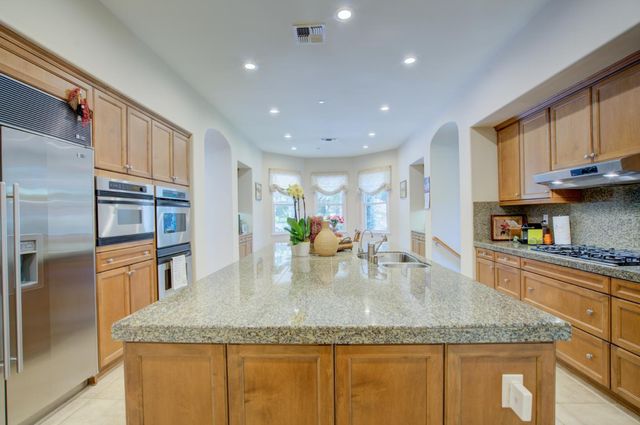 a kitchen with stainless steel appliances granite countertop a sink refrigerator and cabinets