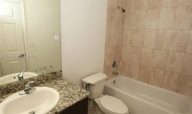 a bathroom with a granite countertop toilet sink and bathtub