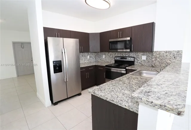 a kitchen with stainless steel appliances kitchen island granite countertop a refrigerator and a stove top oven