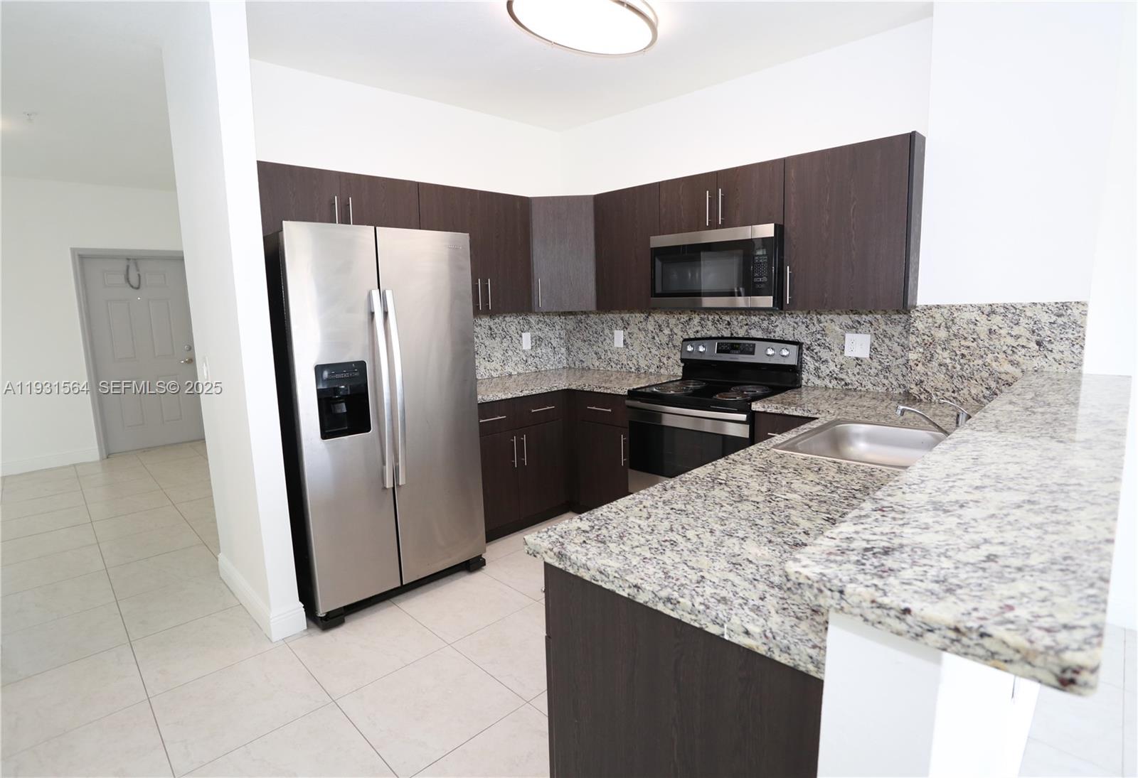 6151 Northwest 182nd Lane, Unit 301 Hialeah, FL 33015 - Photo 4 of 13 a kitchen with stainless steel appliances kitchen island granite countertop a refrigerator and a stove top oven