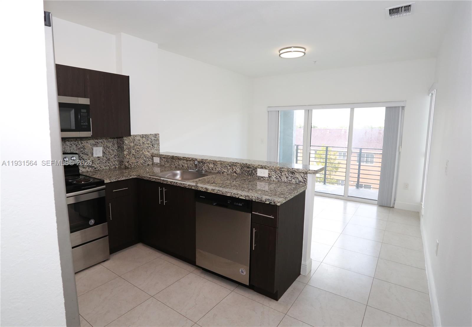 6151 Northwest 182nd Lane, Unit 301 Hialeah, FL 33015 - Photo 5 of 13 a kitchen with granite countertop a sink and a stove
