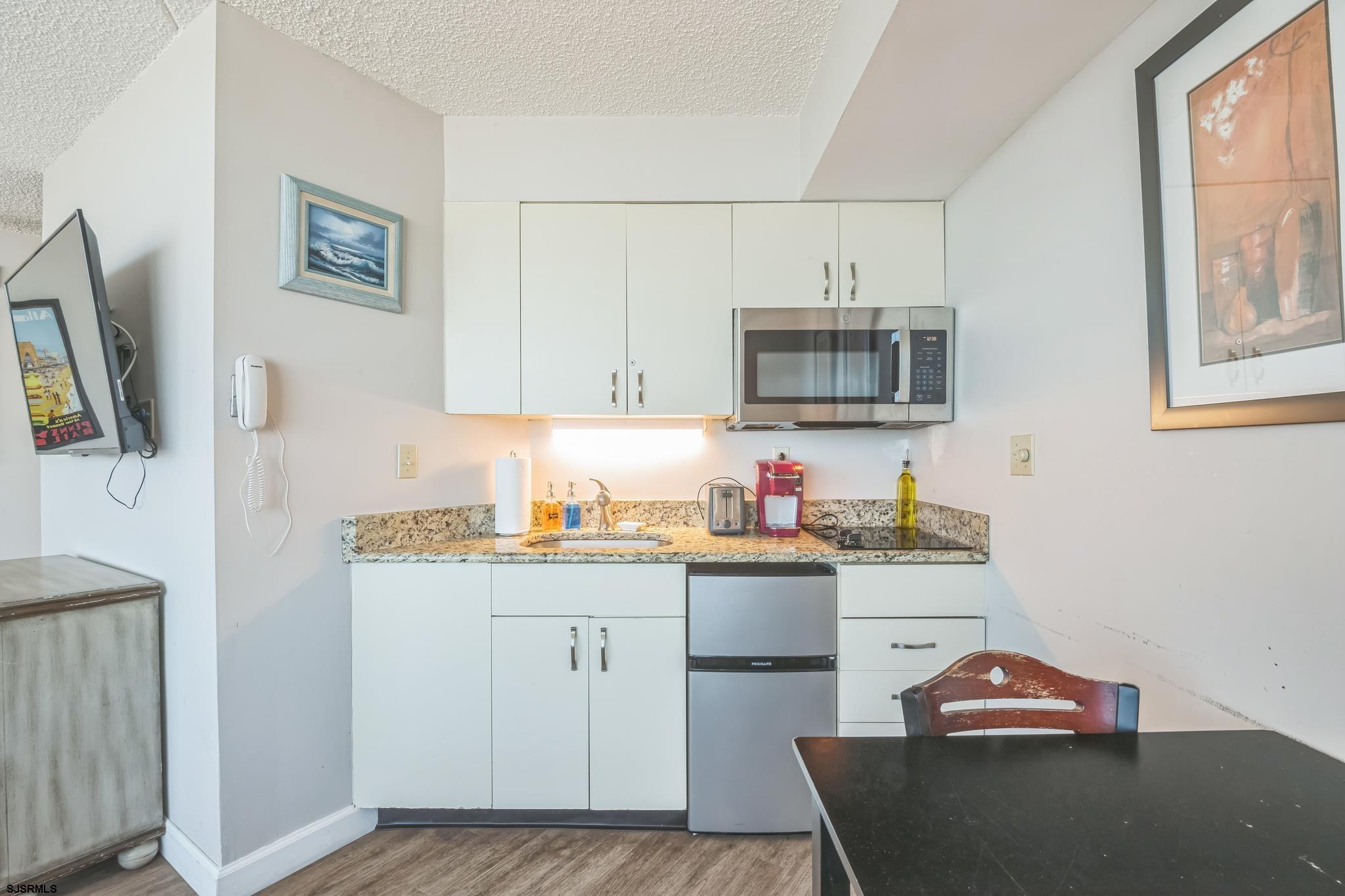 1515 Boardwalk, Unit 1004 Atlantic City, NJ 08401 - Photo 14 of 19 a kitchen with stainless steel appliances granite countertop a stove top oven a sink dishwasher and microwave with wooden floor