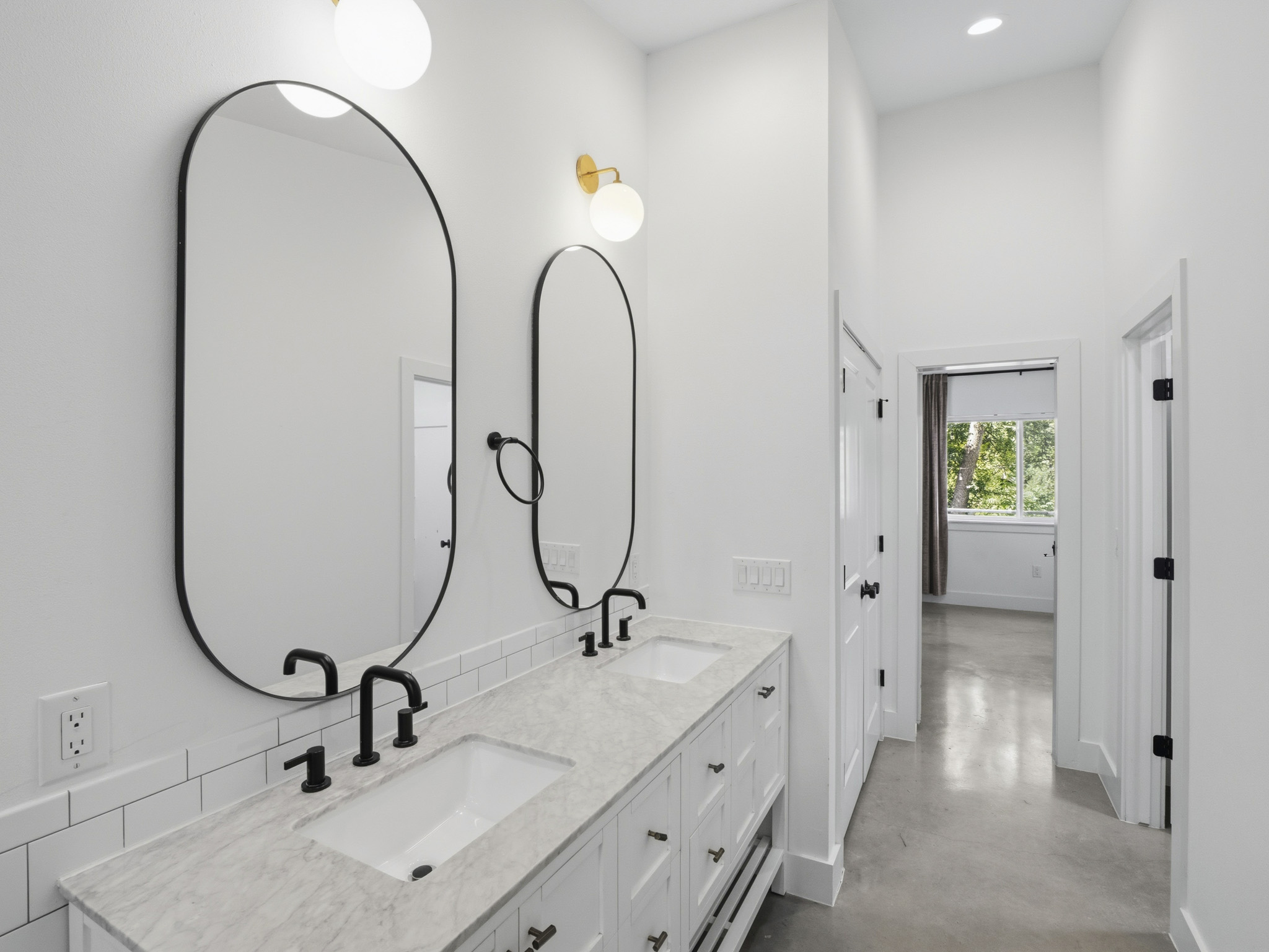 5005 Lott Avenue, Unit 2 Austin, TX 78721 - Photo 15 of 25 Marble countertops and dual sinks elevate this primary bathroom, leading to a naturally illuminated hallway beyond.