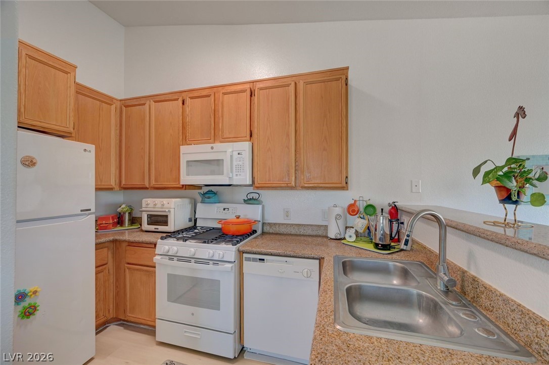 3318 North Decatur Boulevard, Unit 2072 Las Vegas, NV 89130 - Photo 11 of 50 A well-appointed kitchen features ample wood cabinetry, granite counters, and modern appliances, perfect for everyday culinary needs.