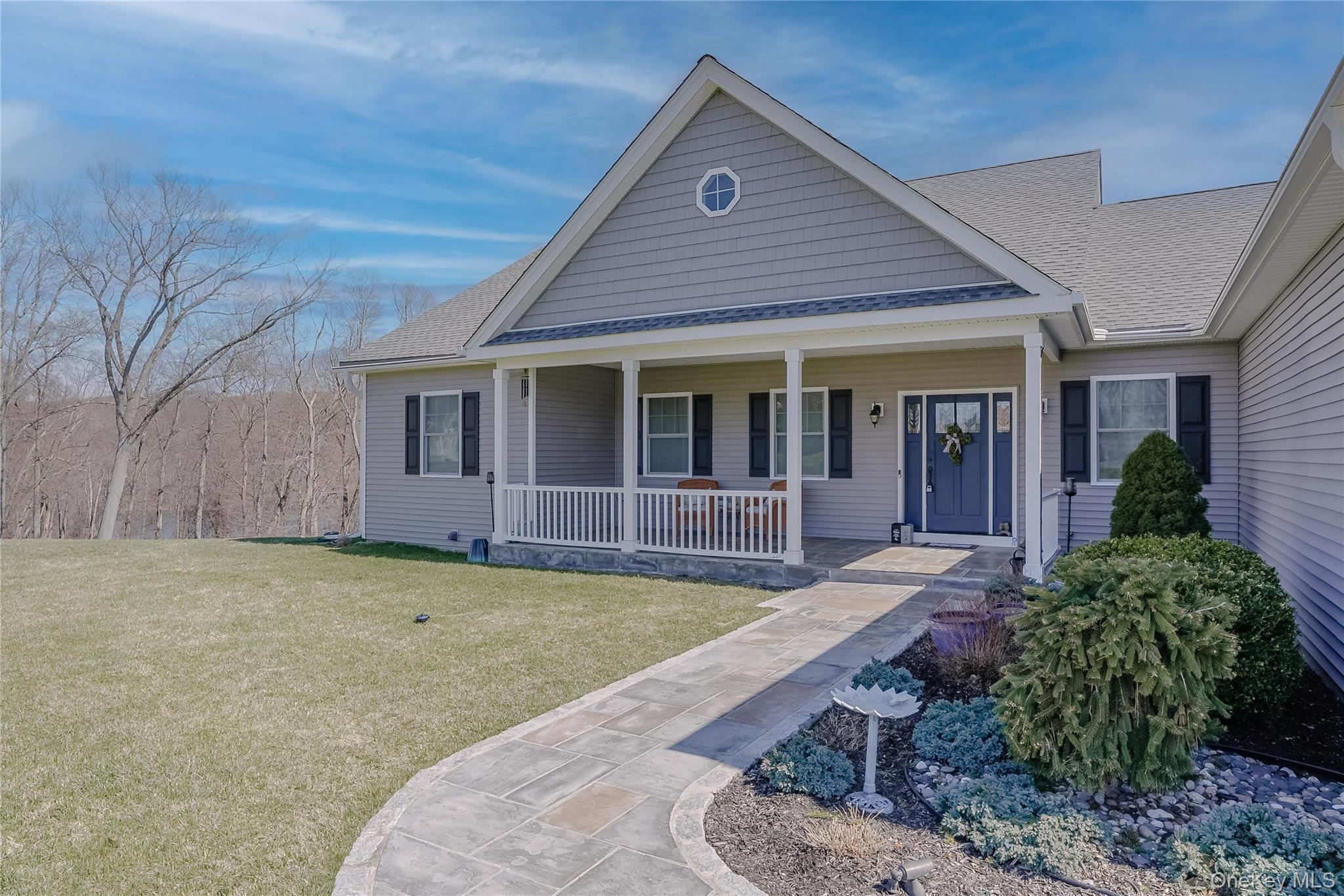 23 Swan Holw Road New Windsor, NY 12553 - Photo 4 of 28 The gracious front porch serves as an extension of the home’s living space, offering a serene setting for quiet mornings and relaxed evenings, all while overlooking the beautifully maintained grounds.