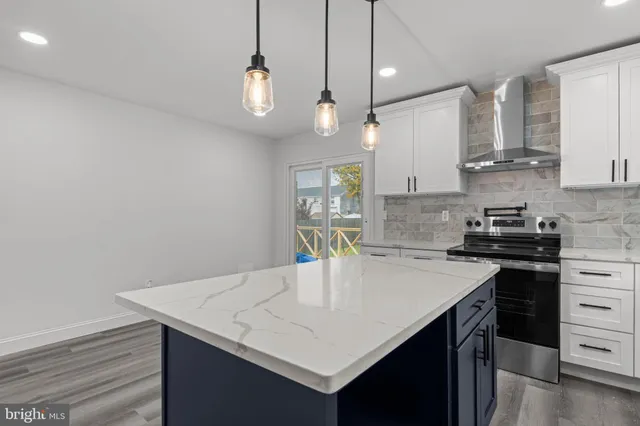 a kitchen with granite countertop cabinets a sink dishwasher a stove and a dining table with wooden floor