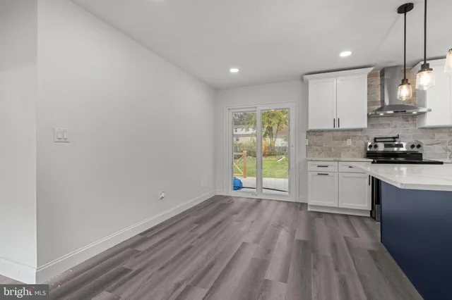 a kitchen with granite countertop a stove a sink and white cabinets with wooden floor