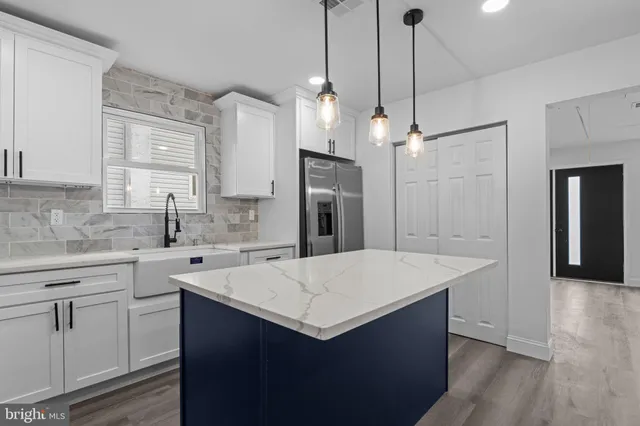 a kitchen with a sink a center island a stove a refrigerator cabinets and a wooden floor