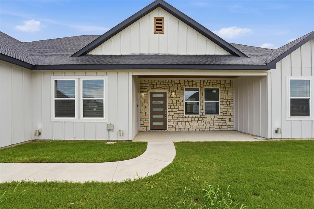 532 Highview Court Godley, TX 76044 - Photo 5 of 39 Modern farmhouse exterior featuring vertical white siding, stone accents, dark-trimmed windows, a covered entry, and a dark shingled roof