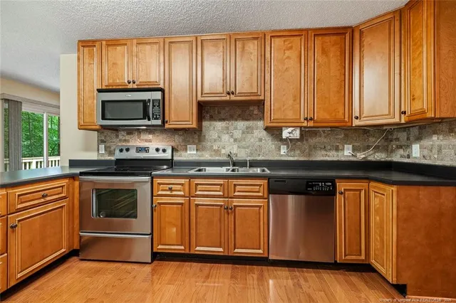 a kitchen with stainless steel appliances granite countertop wooden cabinets a sink and a stove