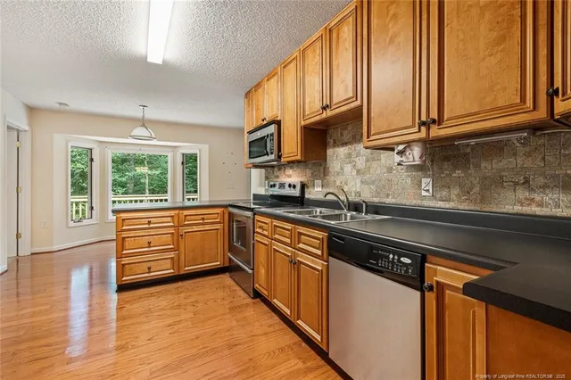 a kitchen with stainless steel appliances granite countertop a stove a sink and white cabinets with wooden floor