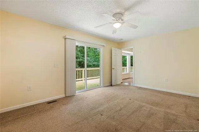 an empty room with windows and ceiling fan