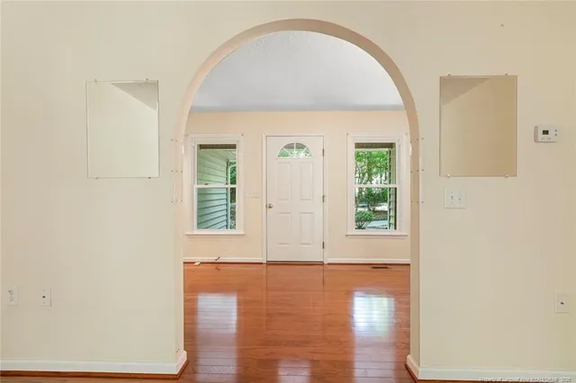 a view of an empty room with wooden floor and a window