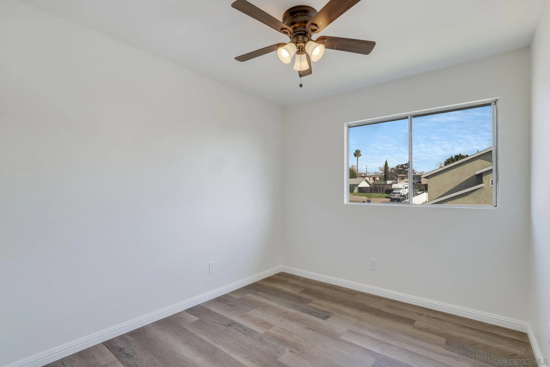 2305 Peppermint Lane Lemon Grove, CA 91945 - Photo 16 of 25 an empty room with a chandelier fan and wooden floor