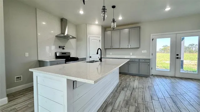 a large white kitchen with kitchen island a sink dishwasher a stove and white countertops with wooden floor