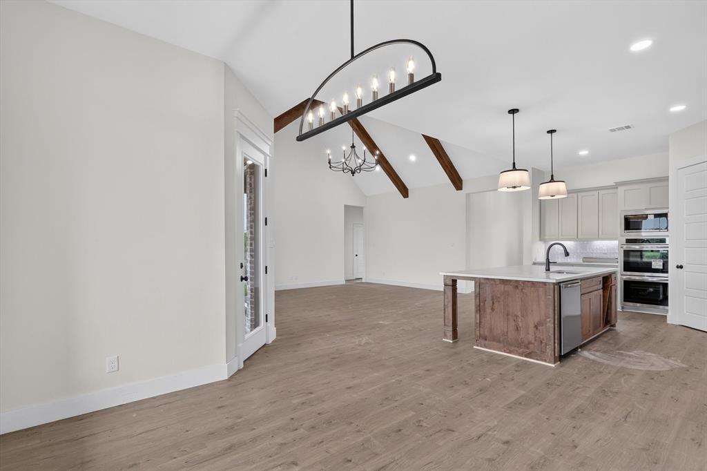 471 Red Bird Drive Springtown, TX 76082 - Photo 15 of 35 Open-concept living space featuring wood-finish flooring, vaulted ceilings with exposed beams, and contemporary lighting