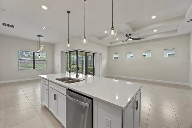 a kitchen with stainless steel appliances granite countertop a refrigerator a sink dishwasher a stove and white cabinets with wooden floor