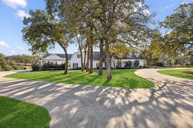a view of a house with a big yard and large trees