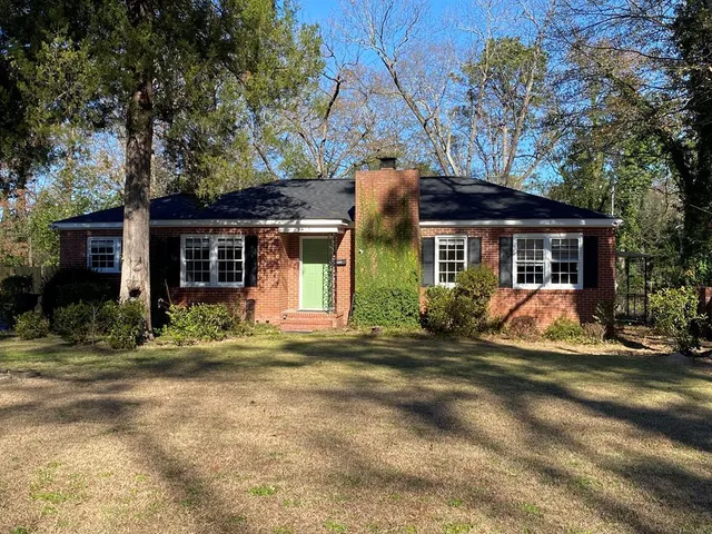 a front view of a house with a garden and trees
