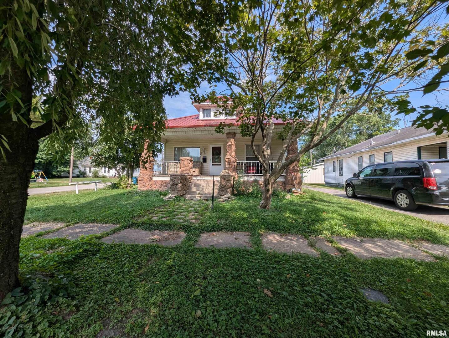 a front view of a house with a garden and trees