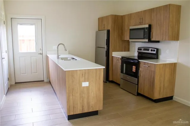 a kitchen with stainless steel appliances a stove a microwave a sink a refrigerator and dishwasher