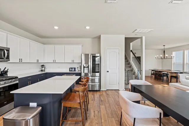 a kitchen with stainless steel appliances wooden floor dining table and chairs
