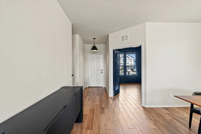 a view of a hallway with wooden floor and a bathroom
