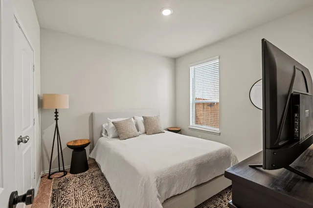 a bedroom with a bed and a flat tv screen on the dresser