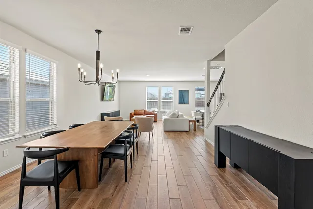 a view of a dining room and livingroom with furniture wooden floor a chandelier