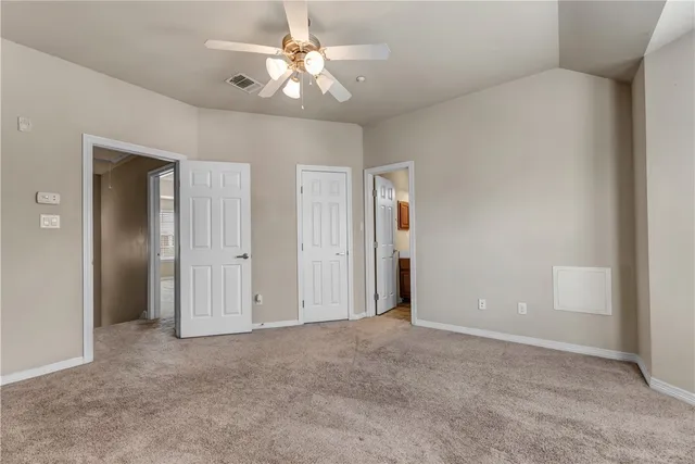 an empty room with closet and a ceiling fan