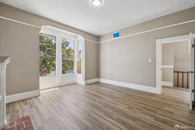 a view of an empty room with wooden floor and a window