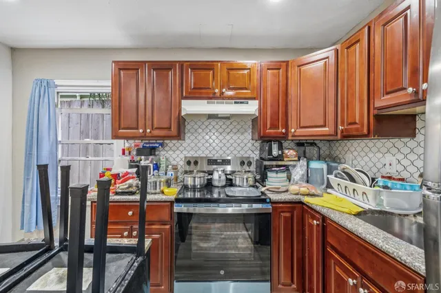 a view of a backyard with table and chairs potted plants and large tree