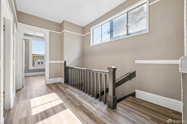 a view of a hallway with wooden floor and stairs