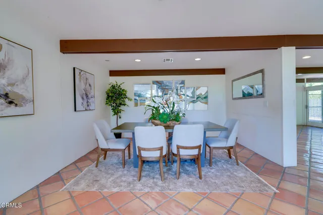 a view of a backyard with table and chairs potted plants and a floor to ceiling window