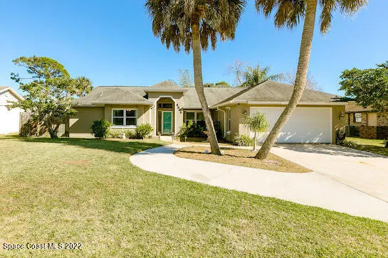 a front view of a house with a yard and palm trees