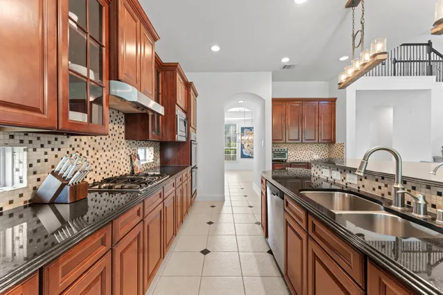 a kitchen with stainless steel appliances a sink a stove and cabinets