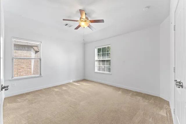 an empty room with windows and fan