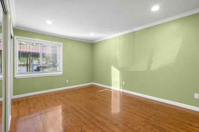 a view of empty room with wooden floor and fan