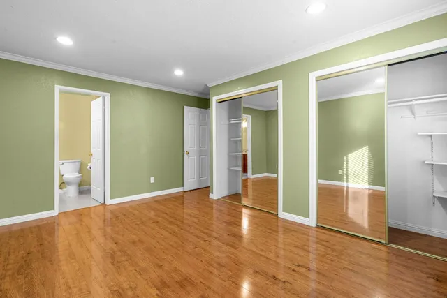 a view of an empty room with wooden floor and a bathroom
