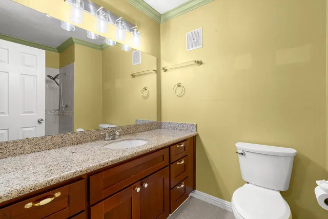 a bathroom with a granite countertop toilet sink and mirror
