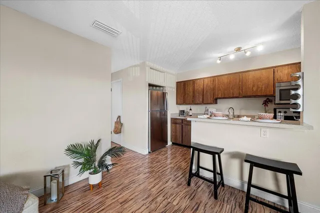 a kitchen with stainless steel appliances a table chairs refrigerator and microwave