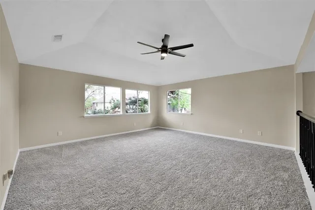 an empty room with windows and ceiling fan