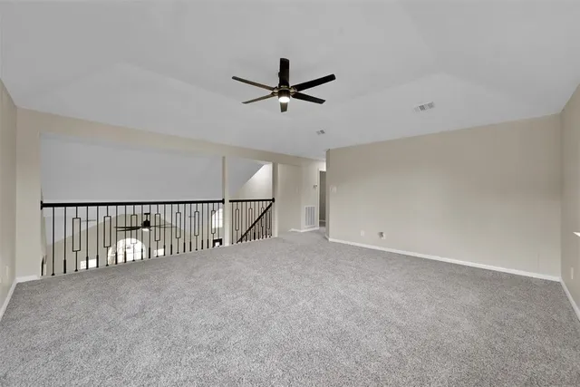 an empty room with ceiling fan and windows